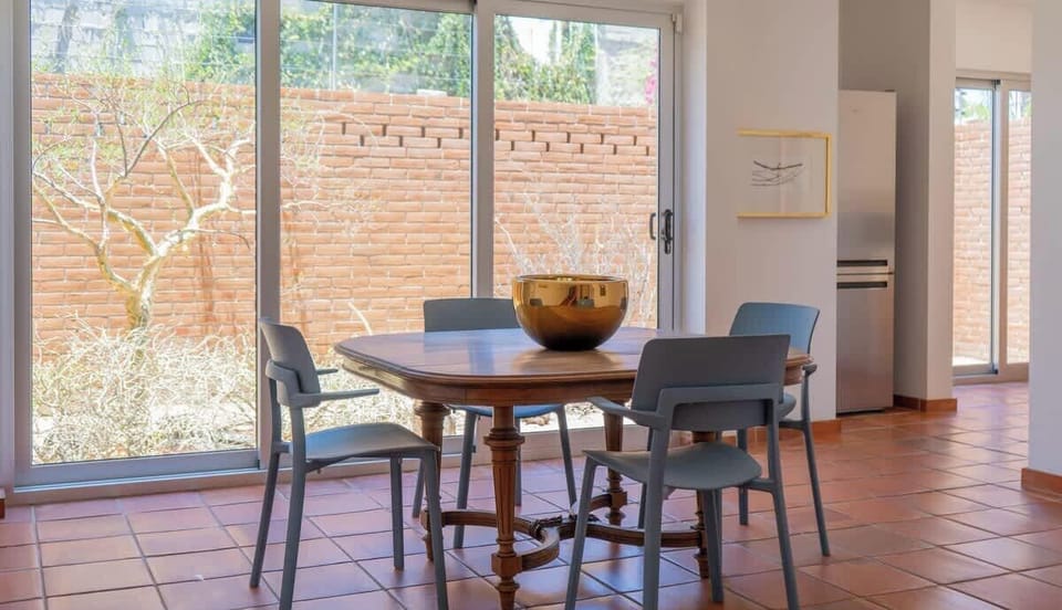 Open layout with a dining table for four, views of the enclosed yard, and plenty of natural light.