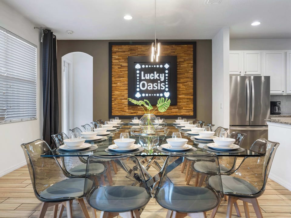 Stylish dining area w/ glass table set for many & eye-catching wall feature