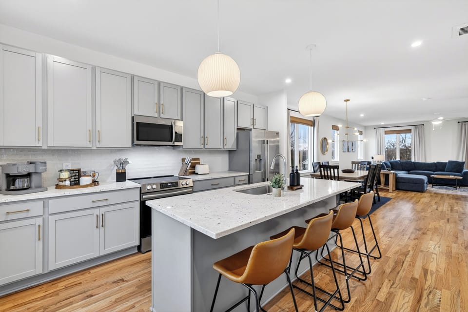 The bright open-concept kitchen features a large island with seating and flows seamlessly into the dining and living areas.