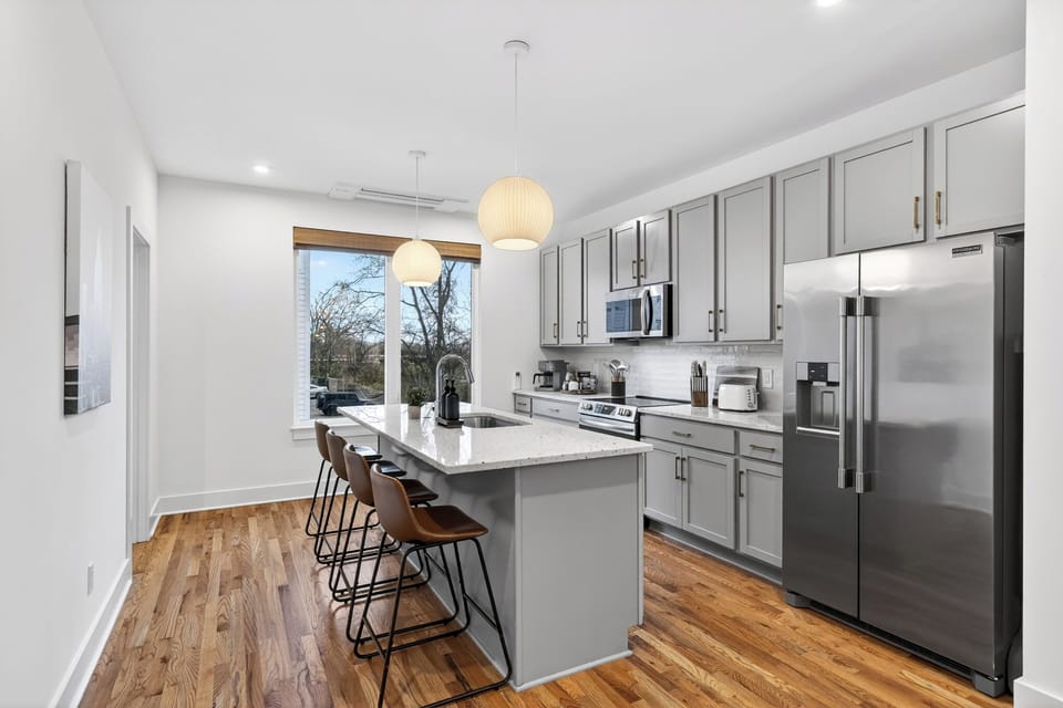 The sleek kitchen offers stainless steel appliances, generous prep space, and island seating for easy mornings and group meals.