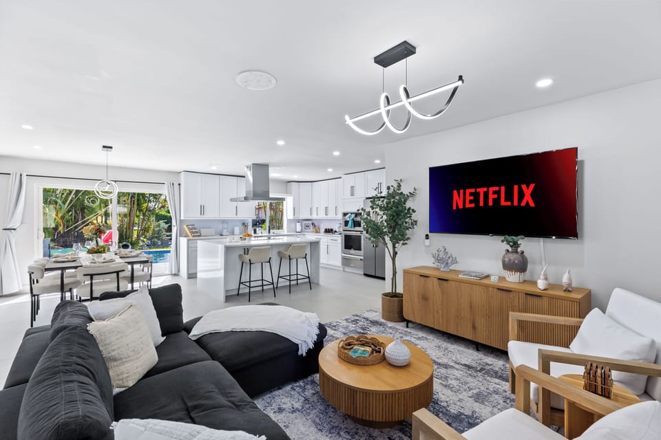 Bright, modern living room with a big-screen TV—perfect for movie nights after the pool, with an open flow into the kitchen for easy entertaining.