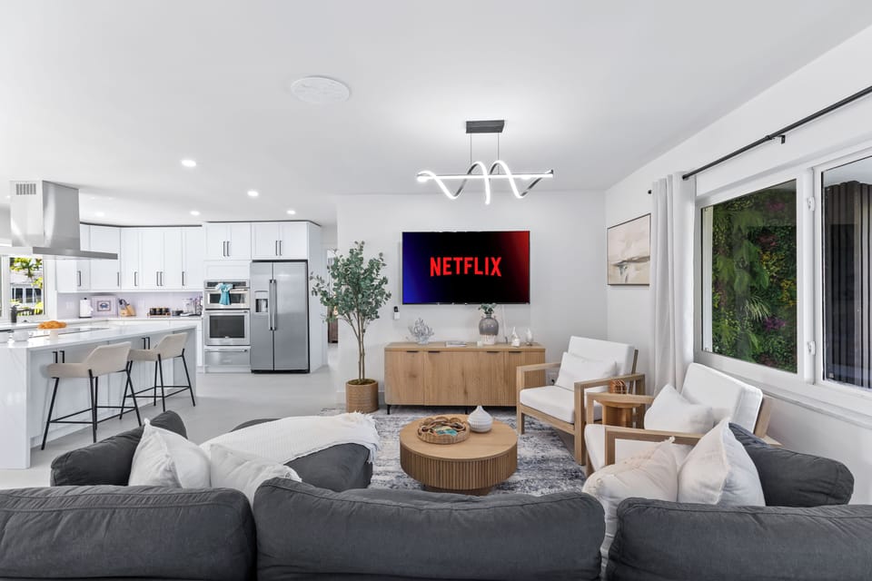 Bright, modern living room with a big-screen TV—perfect for movie nights after the pool, with an open flow into the kitchen for easy entertaining.