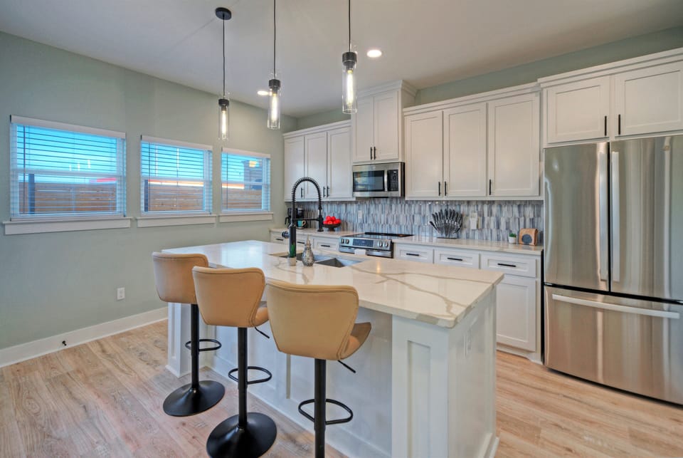 The bright kitchen features a large island, bar seating, and plenty of space for easy meals together.