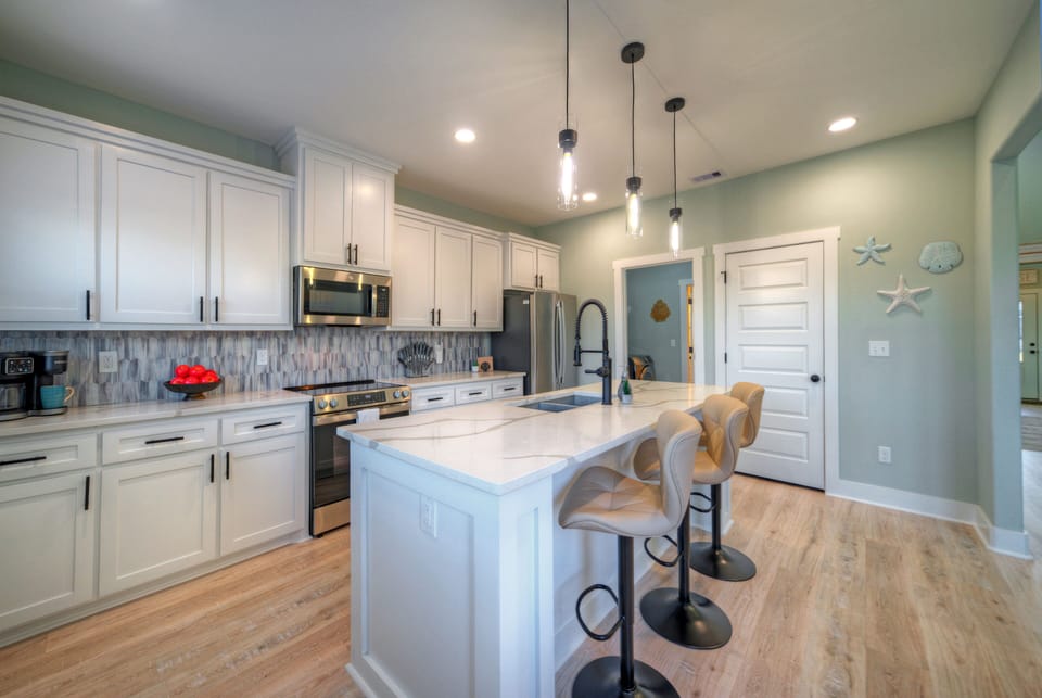 The bright kitchen features a large island, bar seating, and plenty of space for easy meals together.