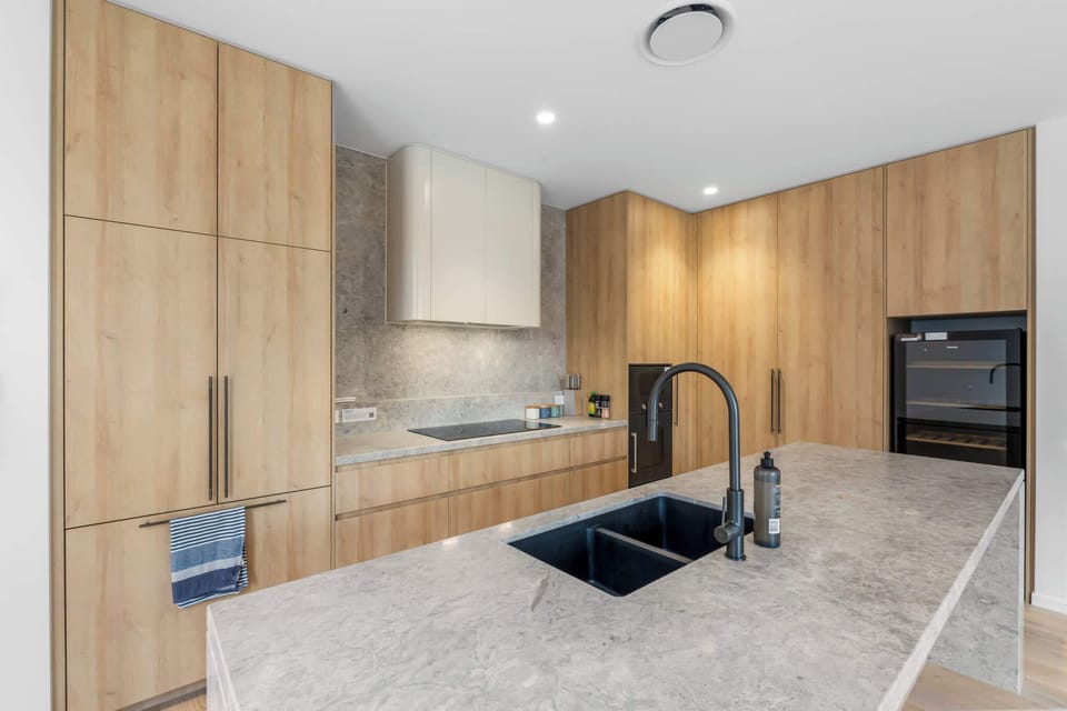 Spacious kitchen with stone splashback, island bench and induction cooktop.