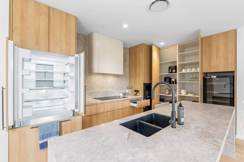 Stone benchtop kitchen with island sink, premium appliances and open dining area. Plenty of cupboard space.