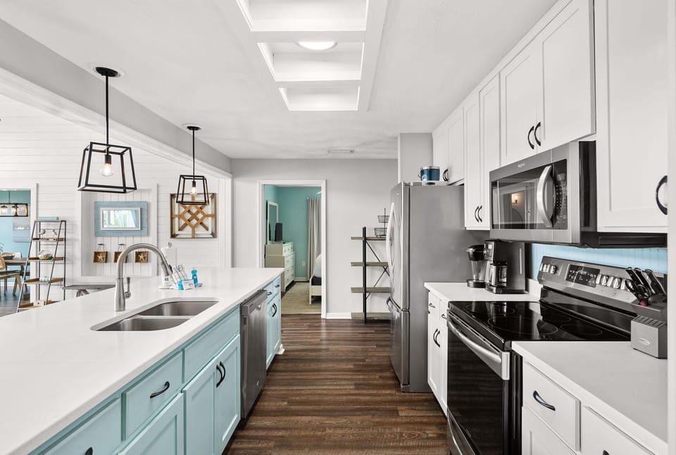 Your fully equipped kitchen features modern appliances, stylish pendant lighting, and charming teal accents - perfect for preparing memorable meals during your stay.