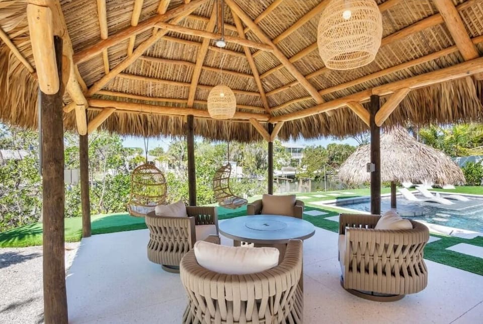 Unwind in your private thatched pavilion with plush seating and wicker pendant lights, where tropical elegance meets poolside comfort.