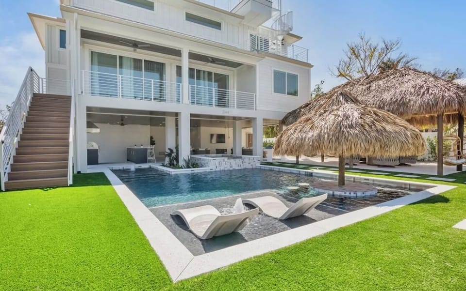 Modern beachhouse featuring a stunning pool with thatched-roof tiki hut, perfect for tropical relaxation and outdoor entertaining.