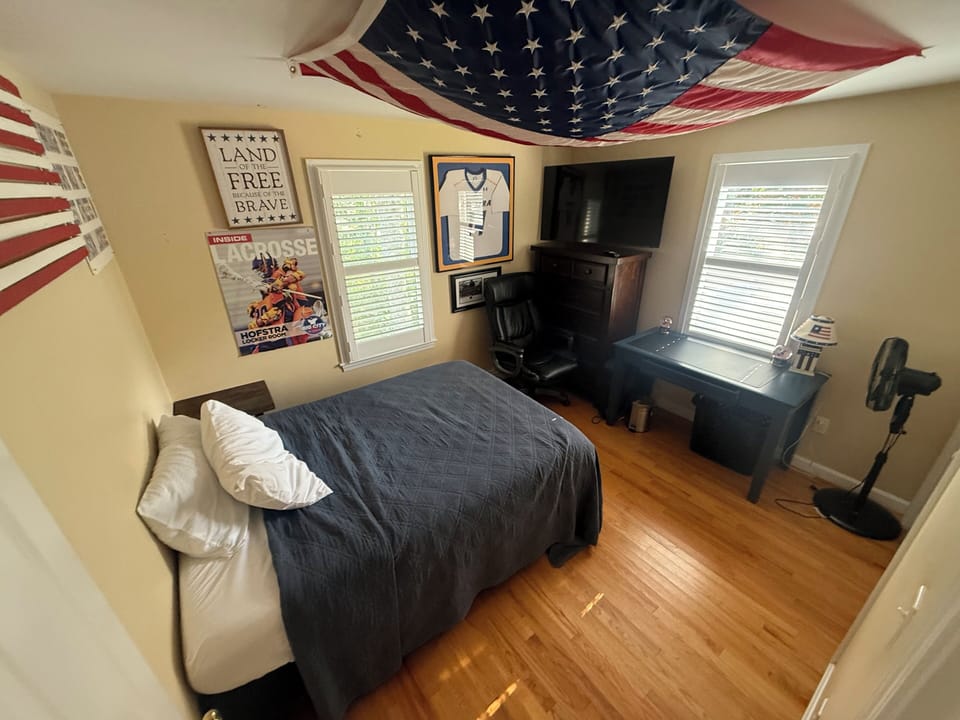 Rest easy in your patriotic retreat with comfortable bedding, entertainment center, and warm morning light streaming through your windows.