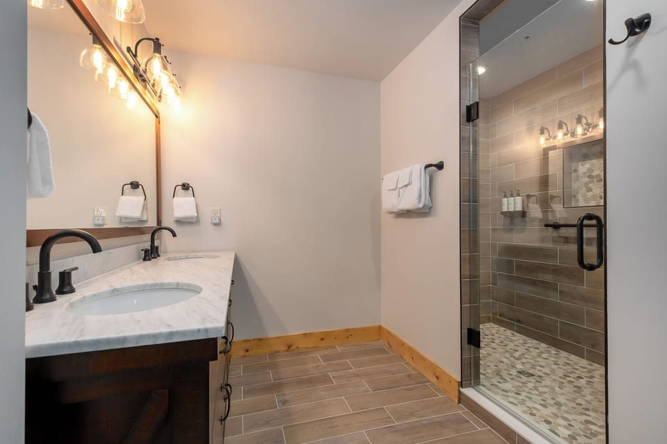 The full bath has a double sink vanity and tile shower.