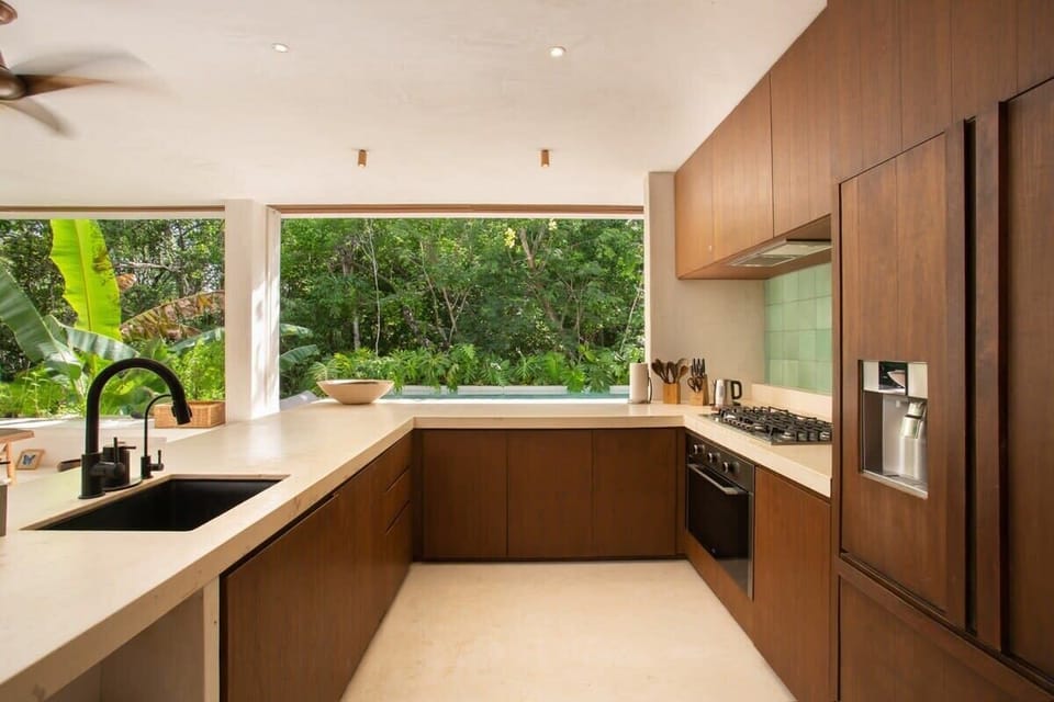 Elegant kitchen with unique finishes. Fully equipped with appliances. Large windows provide an outdoor view.
