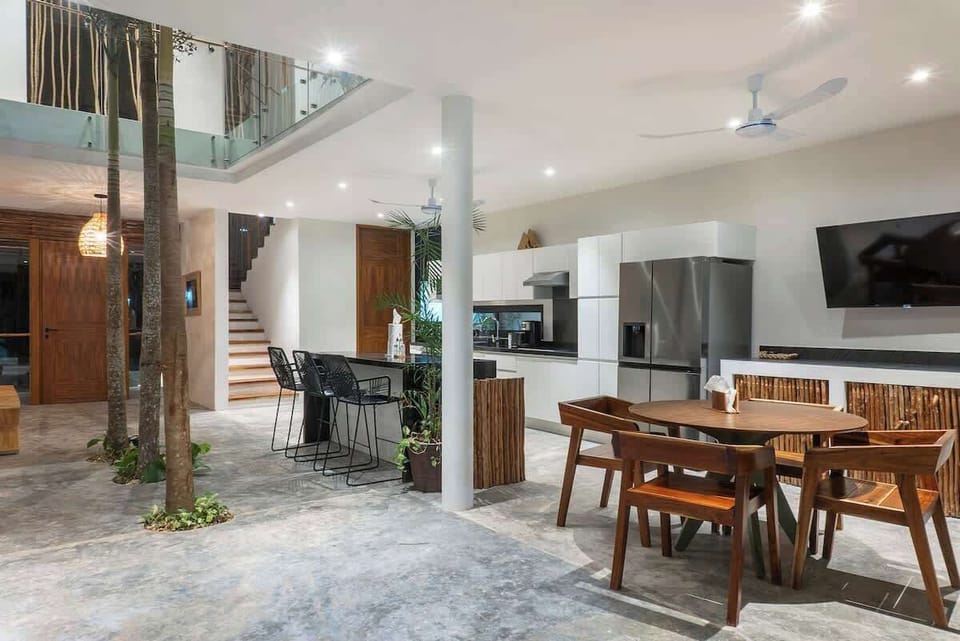 Unique design on the ground floor. The space is integrated with a dining area, kitchen, and natural trees growing in the center, extending up to the second floor.