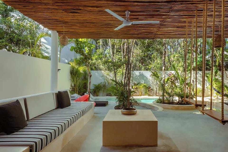 Comfortable and modern covered outdoor living room. It has a ceiling fan and innovative hammocks as part of the seating.