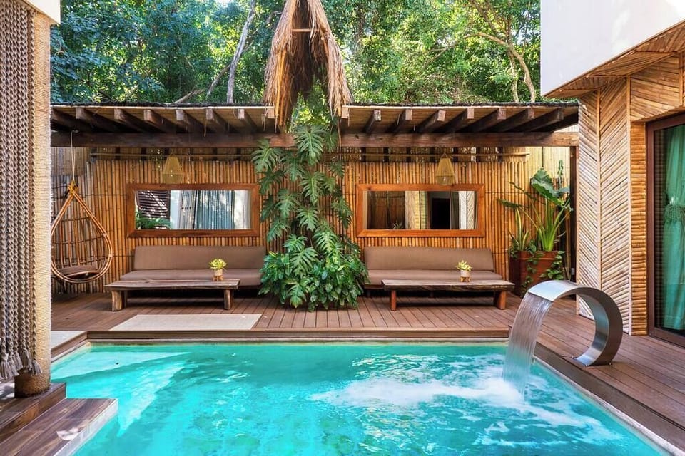 Stylish pool with a waterfall. Surrounded by beautiful decoration and an incredible hanging hammock