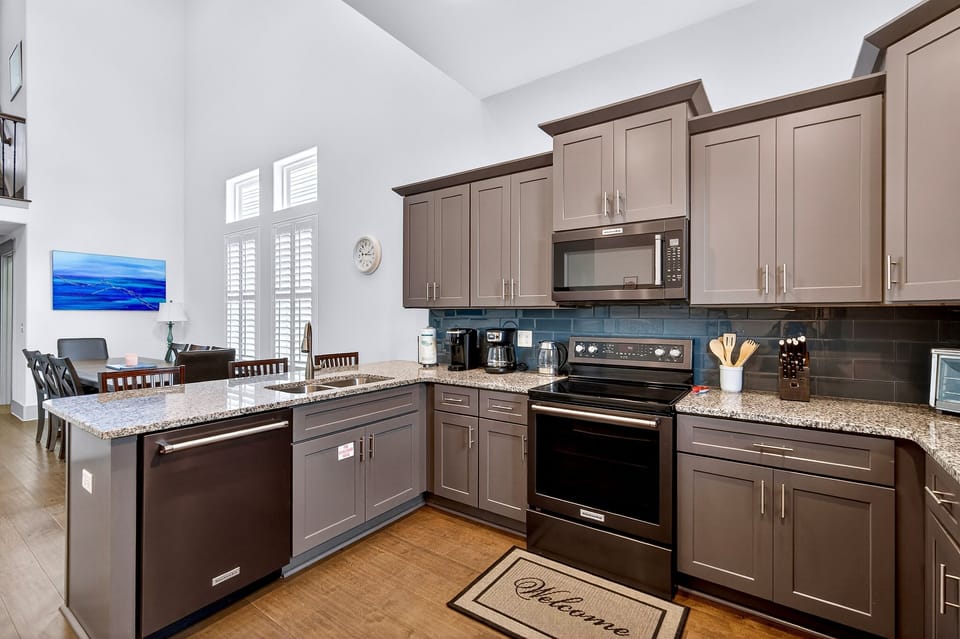 1st Floor - Fully equipped chef’s kitchen with modern appliances, spacious countertops—perfect for cooking meals during your Miramar Beach vacation in Destin. Open layout flows into the dining and living areas for easy entertaining and group gatherings.