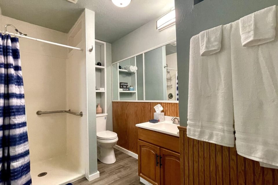 Well lit bathroom with lots of mirrors and hair dryer.
