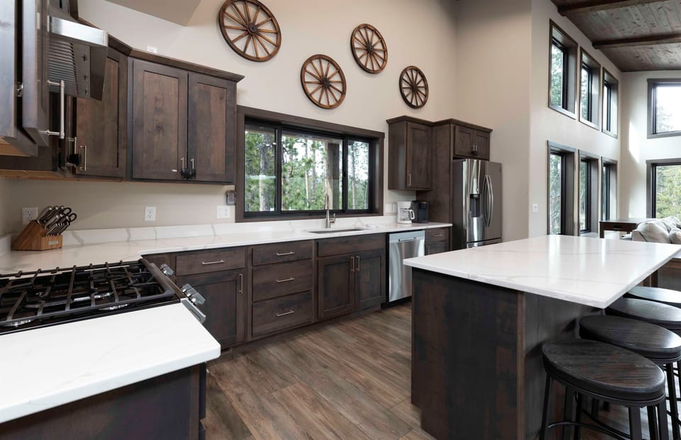 Bright kitchen at Quittin’ Time with a large island, stainless appliances, and windows overlooking the pines. Plenty of counter space for cooking together before heading out to explore the Black Hills.