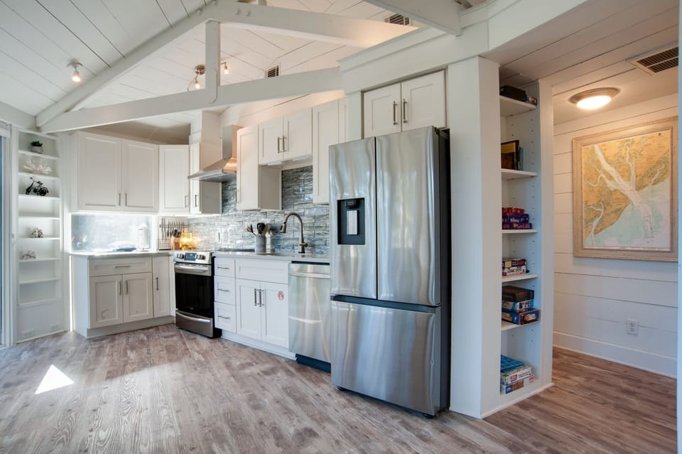 The bright, open kitchen features a full set of appliances and everything you need to cook, surrounded by windows that fill the space with natural light—perfect for a relaxing vacation stay.
