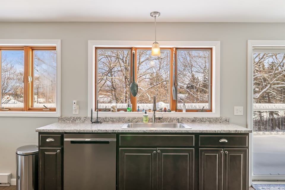 The modern, fully stocked kitchen features ample counter space and full-size appliances, including a dishwasher. Large windows flood the area with natural light, perfect for prepping a fresh catch from Southwest Harbor.