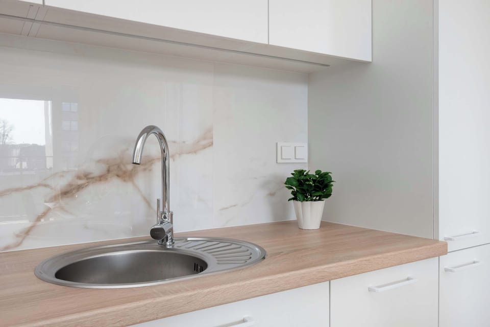A close-up of a kitchenette sink and faucet built into a wooden countertop. Simple decorations and clean surfaces highlight a modern kitchen design.