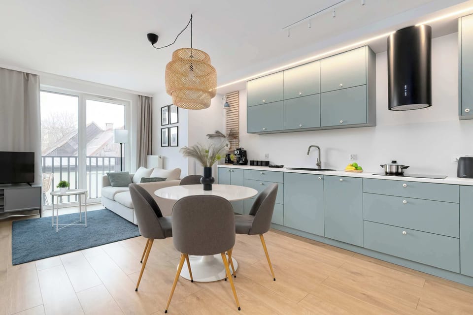 A wider view of the kitchen and dining space with a round table, chairs, and long blue cabinetry stretching across the wall.