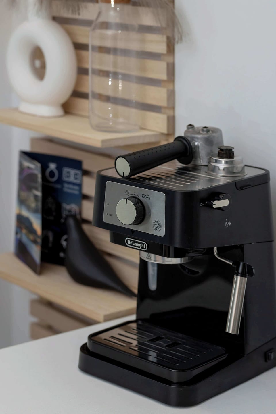 A close-up of a countertop espresso machine placed beside kitchen items, highlighting a coffee-making station.