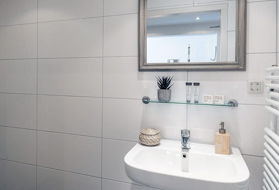 Bright bathroom featuring a stylish vanity, heated towel rack, and a fresh, minimalist design.