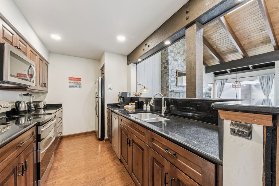 Picture yourself preparing meals in your spacious, fully-equipped kitchen with gleaming granite countertops, warm wood cabinetry, and modern stainless appliances—all bathed in natural light from the vaulted ceiling.
