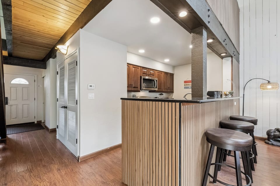 Settle into your open-concept retreat where soaring wood-beam ceilings meet rustic elegance. Gather around the breakfast bar for morning coffee or evening conversation—this warm, inviting space is yours to enjoy.