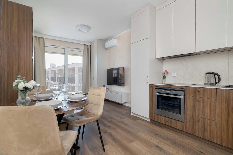 A kitchen and dining area are connected in an open-plan layout. Wooden cabinetry and modern appliances create a warm contemporary look.