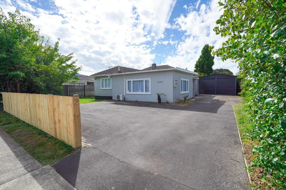 Street view of three bedroom home with onsite parking.