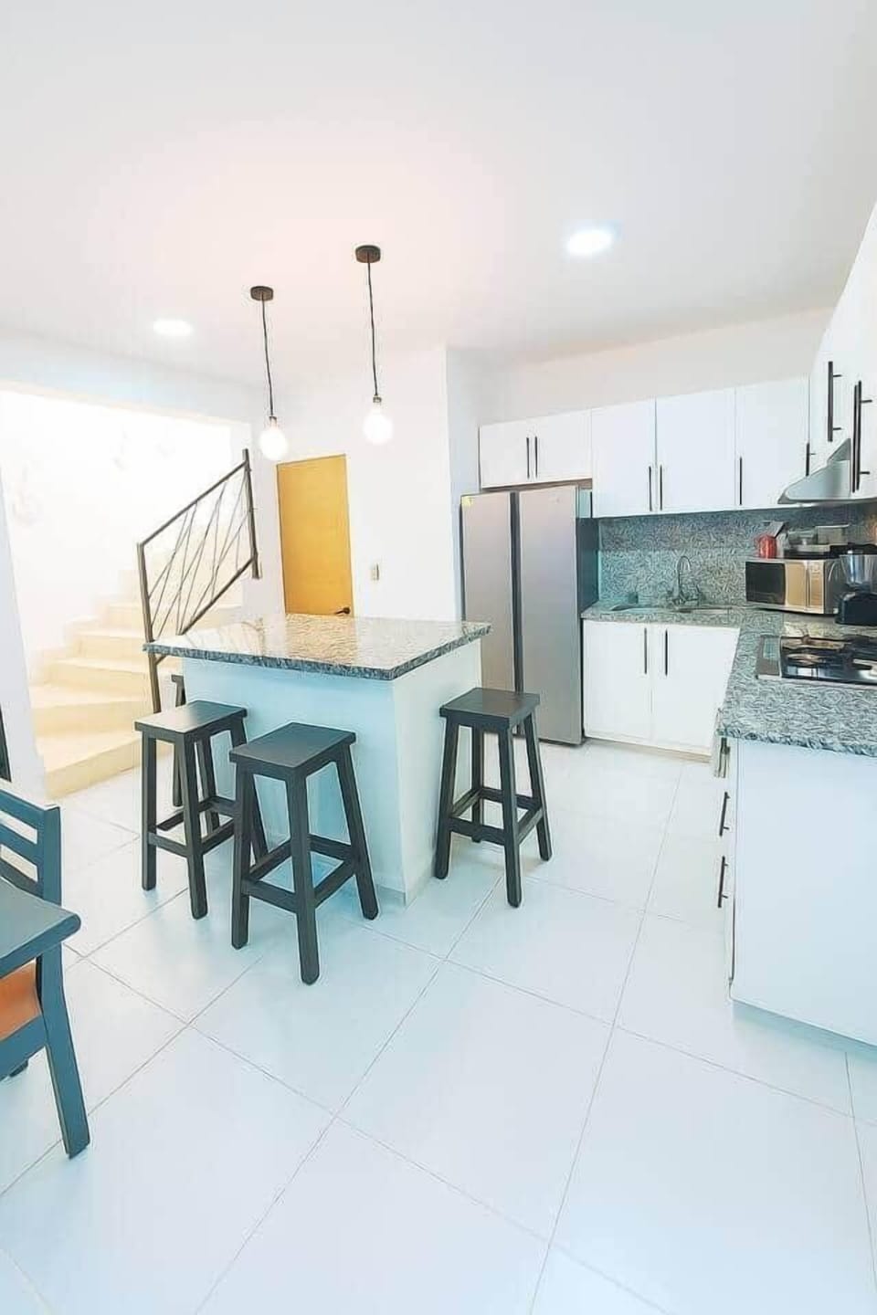 This modern kitchen and living room flow seamlessly into one another, combining functionality and style. Sleek, contemporary cabinetry and high-end appliances elevate the cooking experience, while the inviting design encourages relaxation.