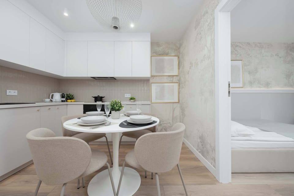 The layout reveals how the kitchen and dining area seamlessly connect to the sleeping quarters through a wide doorway. The consistent use of light wood floors and white walls enhances the sense of space.