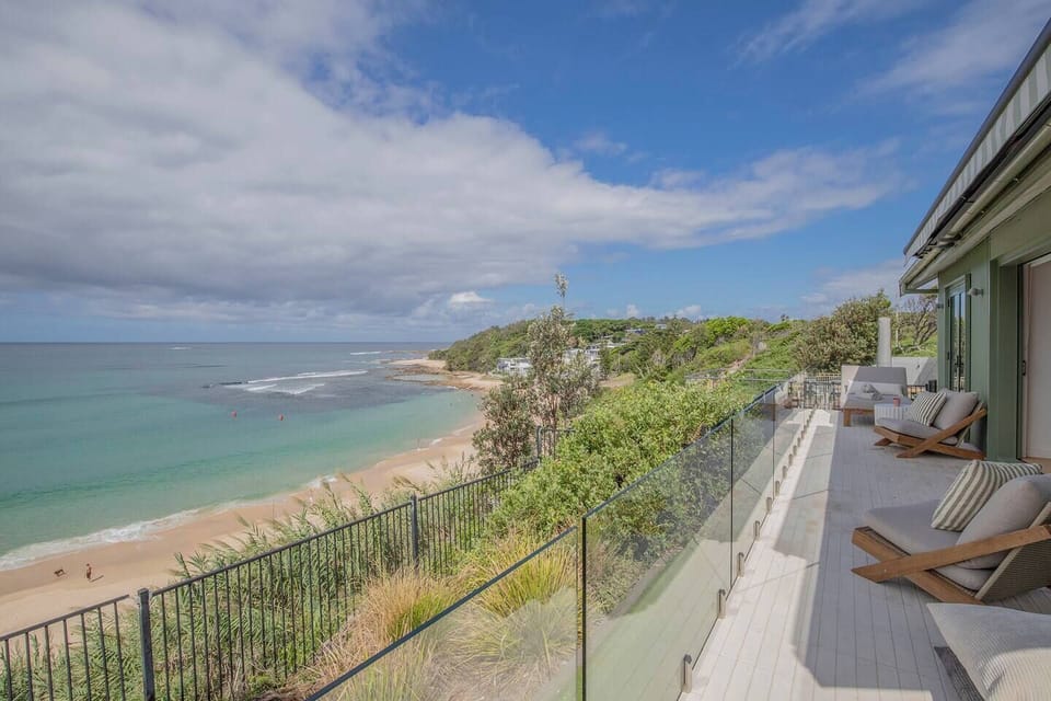 The balcony can be accessed from both the living area and the primary bedroom, offering front-row views of the Pacific and the coastline below.