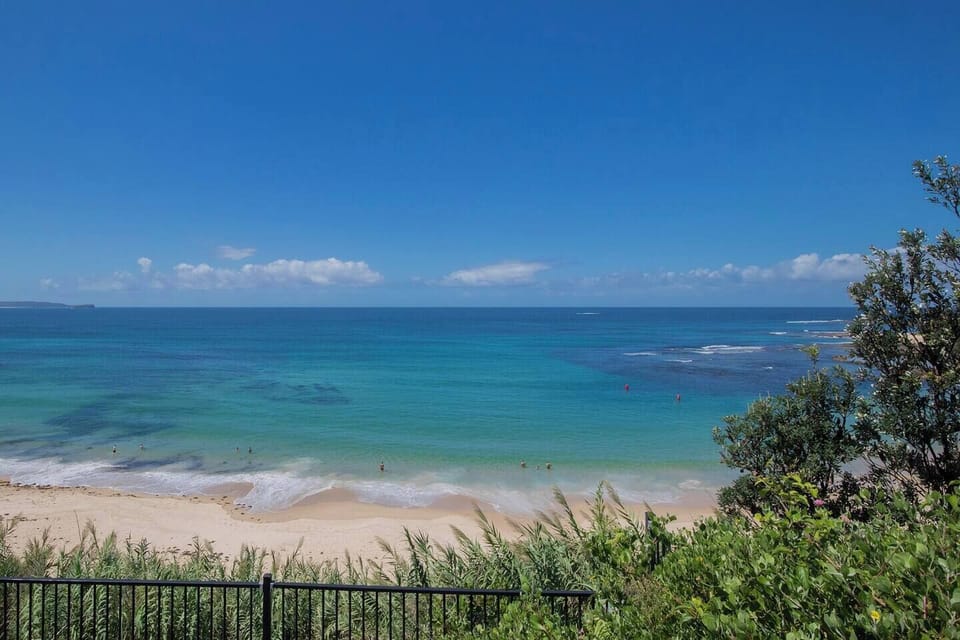 Take in the breathtaking sweep of Norah Head Beach as turquoise waters meet golden sand and the Pacific stretches endlessly toward the horizon.