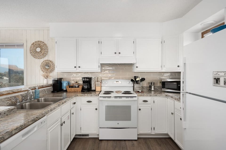 Bright kitchen w/ white cabinetry, modern appliances & plenty of counter space
