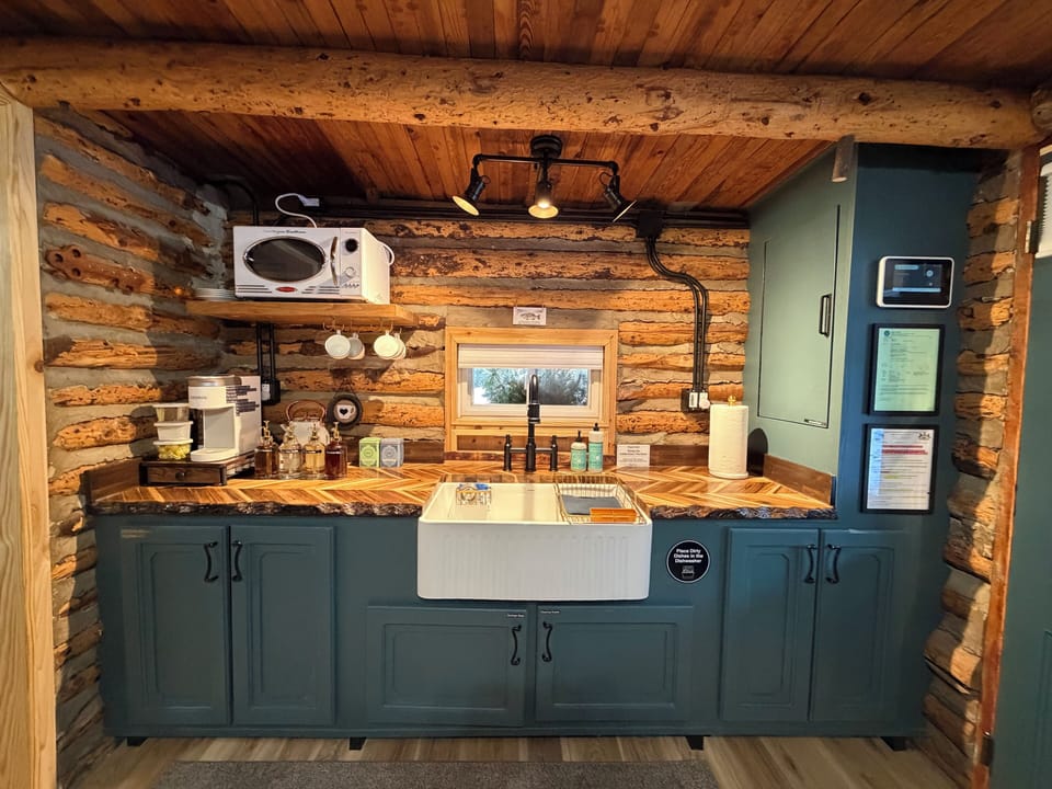 Kitchen sink, cabinet dishwasher, microwave, and coffee station.