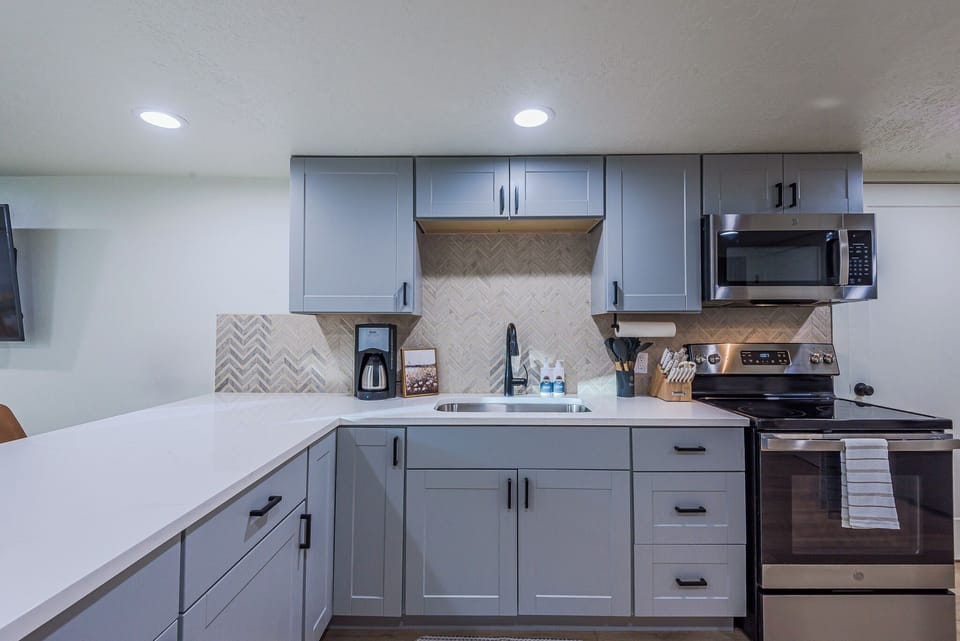 Quartz peninsula, herringbone backsplash, and matte black fixtures. Style meets function.