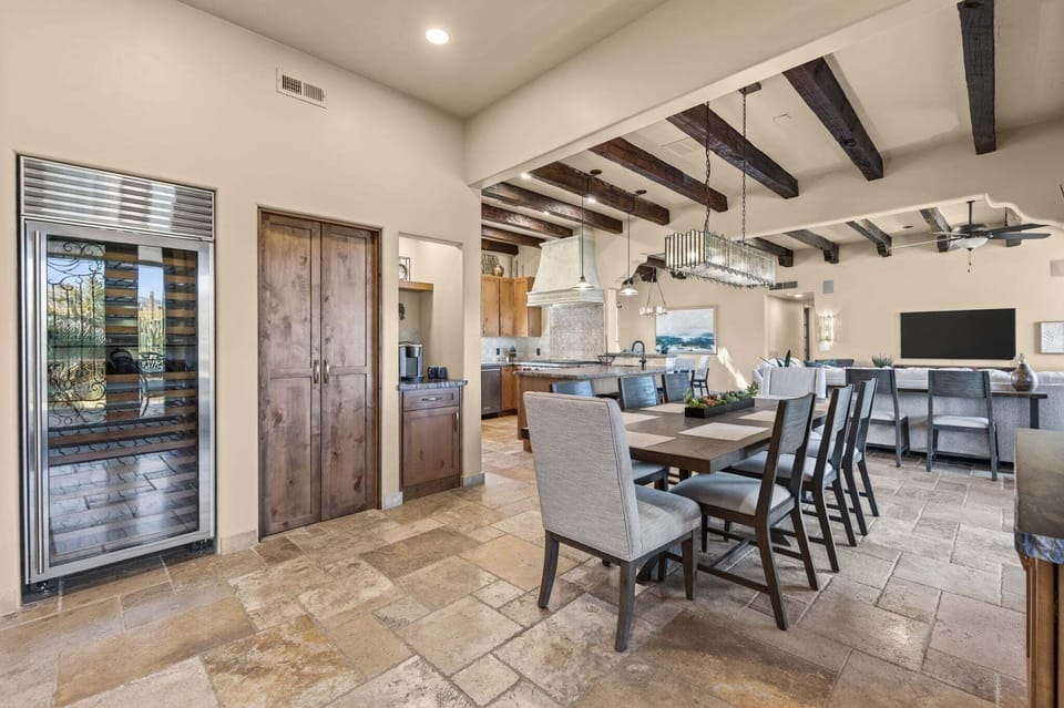 This dining-room angle shows the large table, built-in wine refrigerator, coffee station, kitchen and living area.