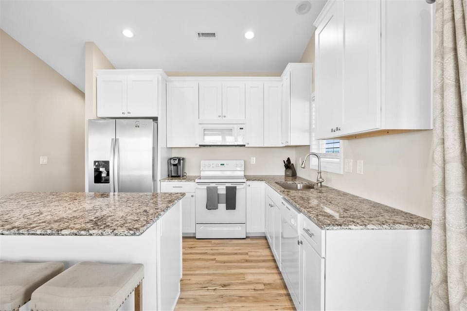 Cook with ease in a spacious kitchen stocked with rental essentials, cookware, utensils, and a coffee maker with complimentary coffee.