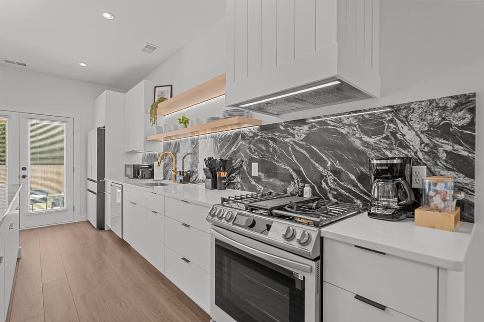 Fully equipped modern kitchen with sleek finishes, stainless steel appliances, and a gas stove.