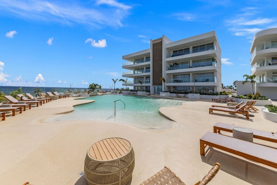 Stunning beachfront pool with loungers and ocean backdrop—perfect for soaking up the sun in a luxurious resort setting.