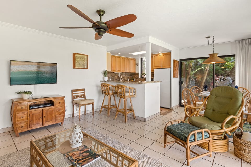 Open living area with ceiling fan, seating, and breakfast bar kitchen.