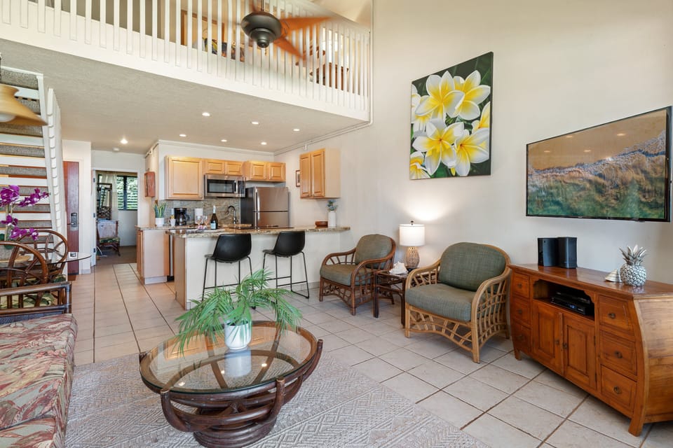 Open-concept living space highlighting airy vaulted ceilings, bright seating options, and smooth flow into the kitchen and loft dining area.