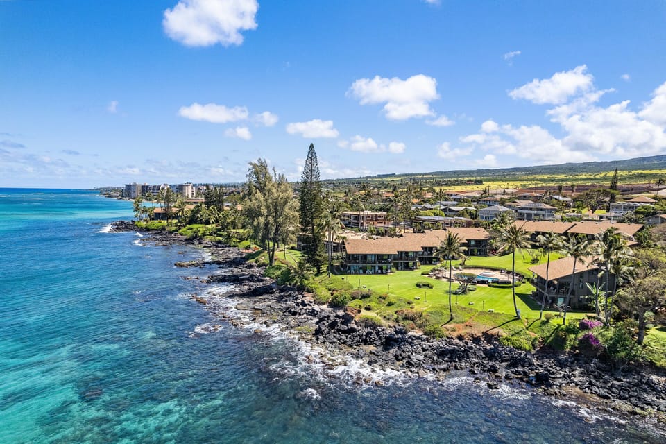 A sweeping aerial perspective showing the stunning turquoise waters, rocky coastline, and oceanfront setting of the property.