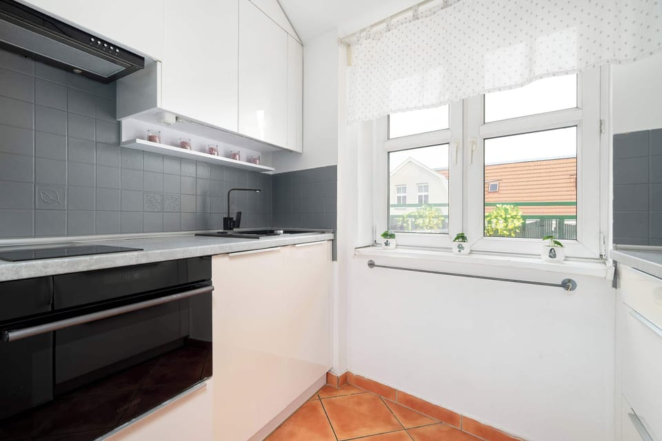 Another angle of the kitchen with white cabinets, a stove, and a clean countertop layout.