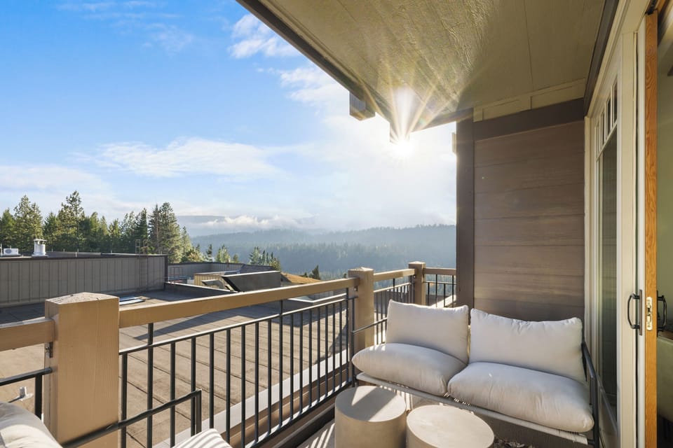 Enjoy peaceful mornings on this inviting balcony, where plush seating and sweeping forest views create the perfect spot to unwind.