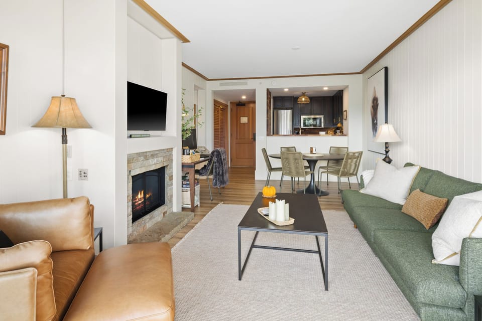 Enjoy the open-concept layout where the cozy living area, stone-framed fireplace, and modern kitchen flow together seamlessly—perfect for cooking, lounging, and connecting.