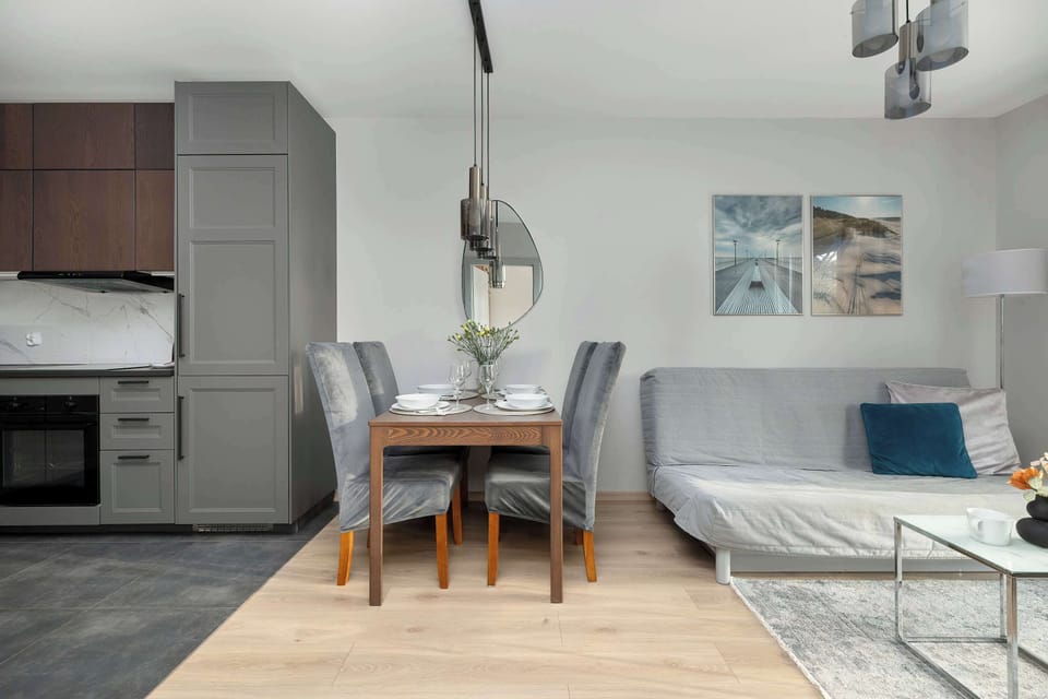An overview of the main living space where the grey kitchen units blend seamlessly with the dining and lounging areas. The cohesive color palette of grey, white, and wood creates a harmonious and inviting interior.